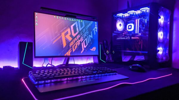 Beleuchteter Gaming-Schreibtisch mit Monitor, Tastatur und Rechner in violettem Licht