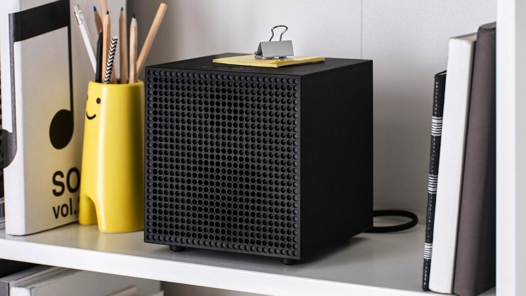 Der IKEA BADKRUKA in Schwarz steht in einem hellen Regal zwischen Büchern und einem gelben Stiftebecher