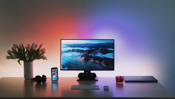 Sony ULT Field 5 am PC: Wo der Partylautsprecher an Grenzen stößt Aufgeräumter Schreibtisch mit Monitor, Tastatur und Kopfhörern bei farbigem Hintergrundlicht