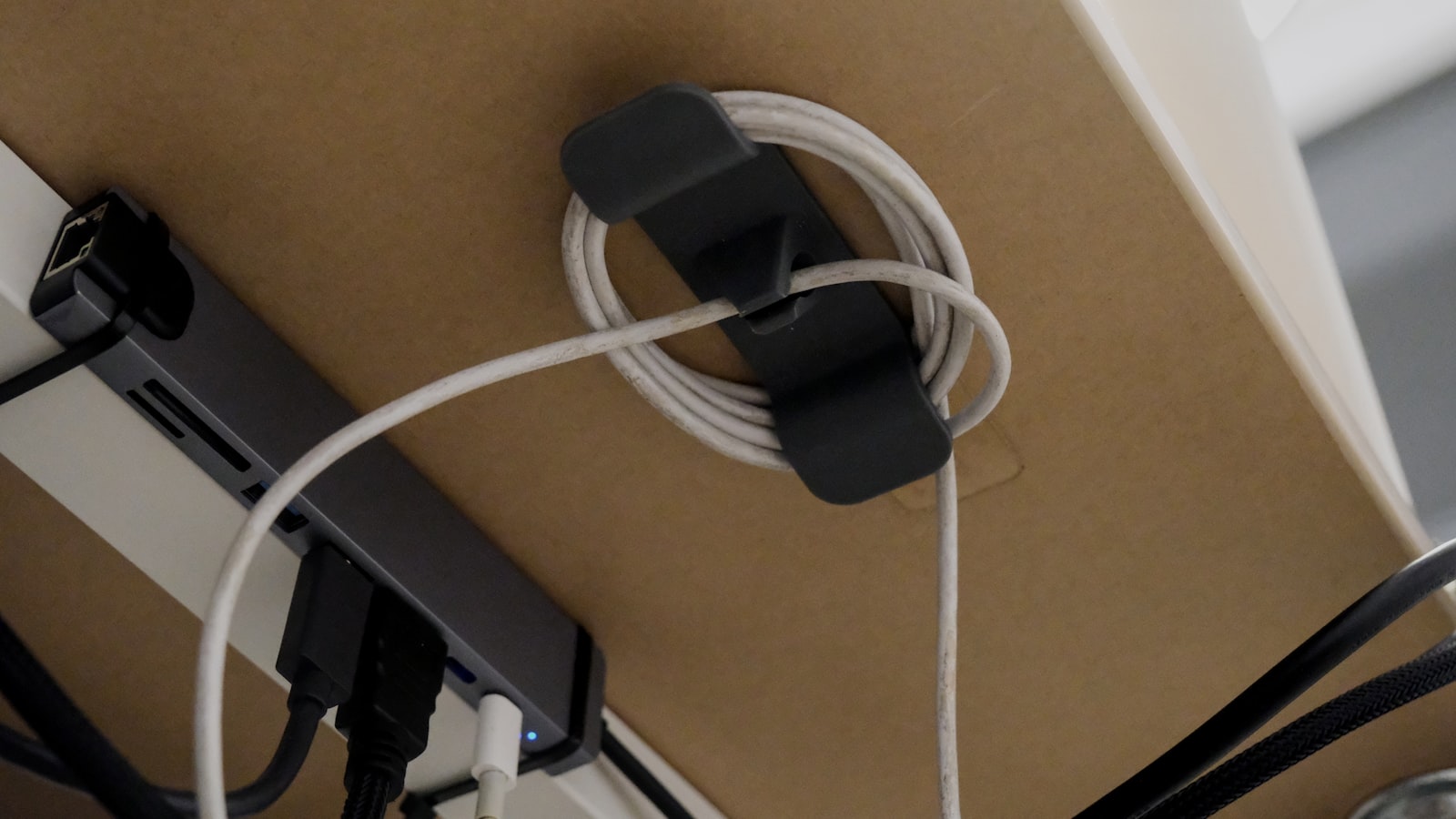 Soundbar oder Stereopaar am PC: Was wann besser klingt Aufgewickeltes Kabel in einem Halter unter einer Tischplatte, daneben ein Anschlussverteiler